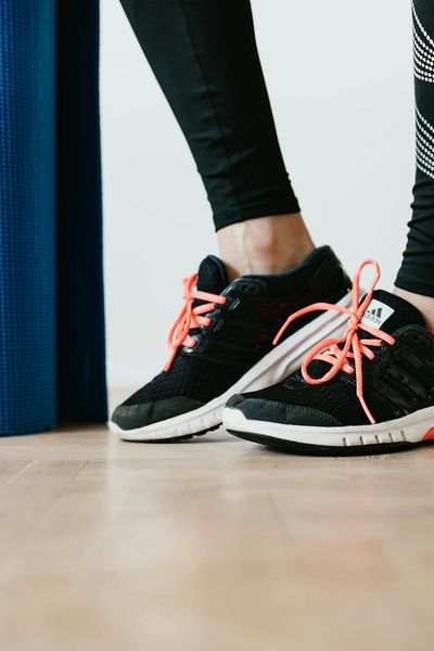 Close-up shot of feet in athletic shoes on a yoga mat, ready for exercise.
