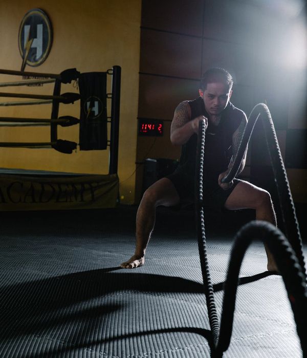 Person in mid-motion during a cardio exercise in a dark studio with amber light.